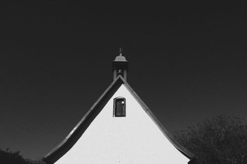 Free Minimalist black and white photo of a church roof with a cross, emphasizing architectural symmetry. Stock Photo