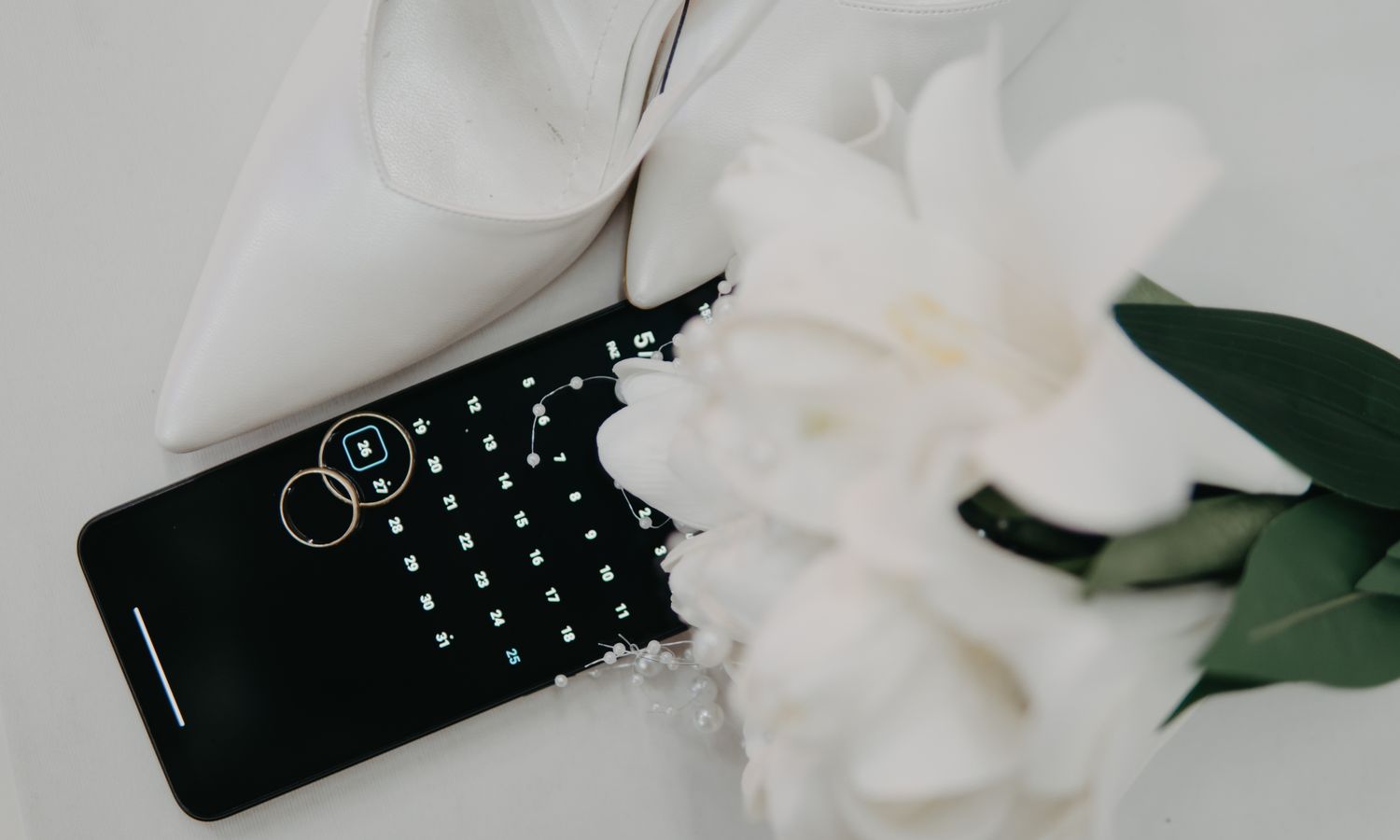 calendario, alianzas y ramo de flores sobre una mesa, símbolos de la planificación de una boda