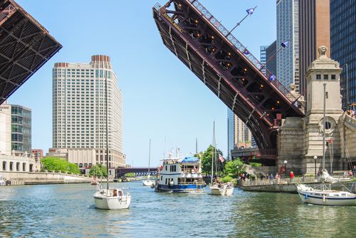Free View of DuSable Bridge raised over the Chicago River with surrounding cityscape and boats. Stock Photo