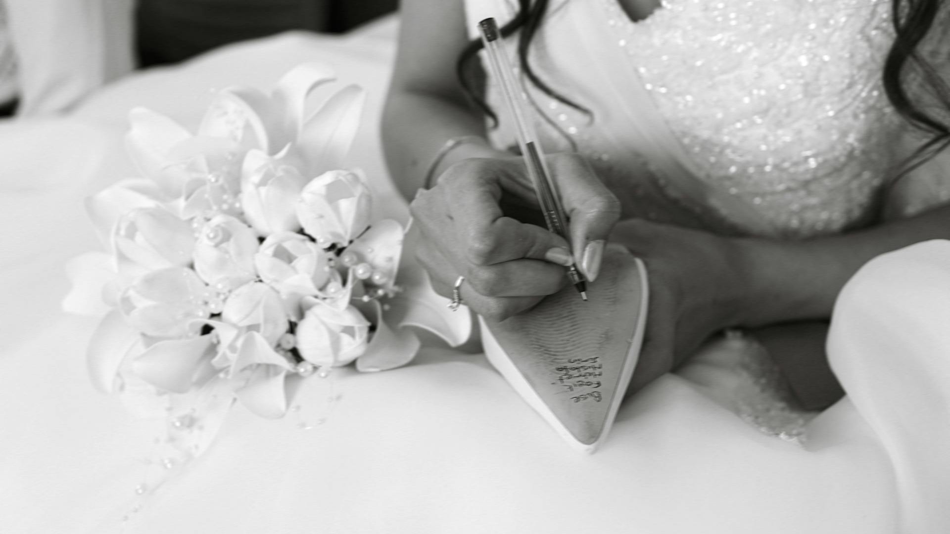 Bride writing names inside high heel shoe