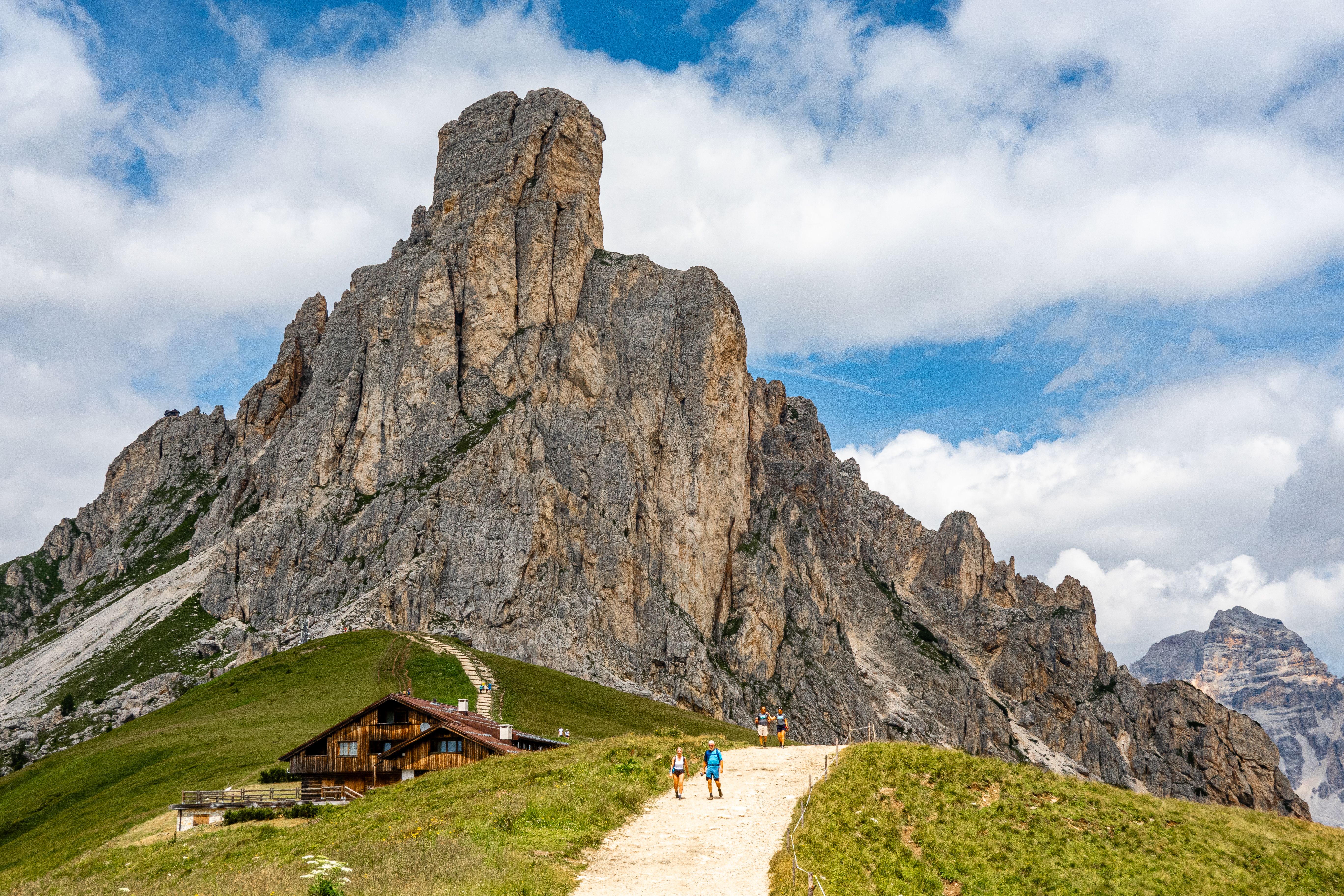 Scenic hiking trail in the Dolomites with rugged peaks and bright sky.
