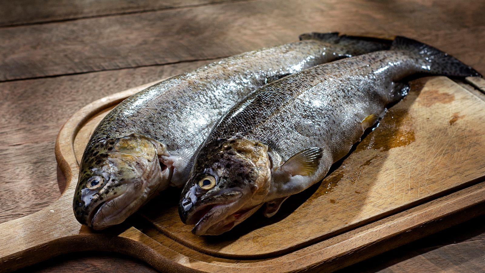 Two whole fresh rainbow trout on a wooden cutting board — photo by Marcelo Verfe on Pexels Two whole fresh rainbow trout on a wooden cutting board