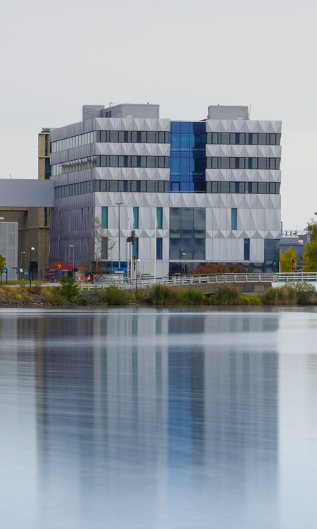 Modern Building Reflecting in Tranquil Water · Free Stock Photo