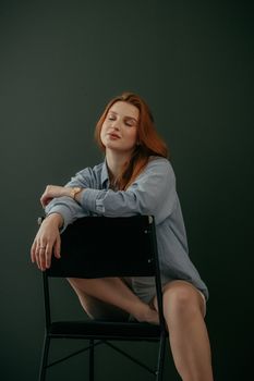 Calm woman sitting comfortably on a chair indoors, wearing casual attire.