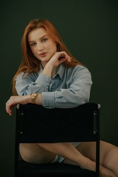 Stylish woman with red hair in casual attire posing indoors.