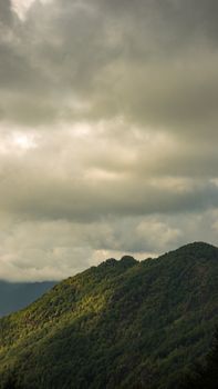 Lush green hills under a dramatic cloudy sky, capturing the serene essence of nature's beauty.