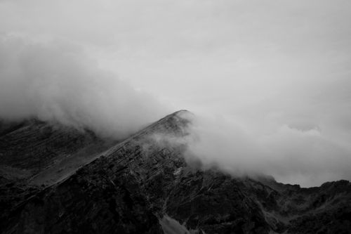 Free Misty clouds envelop rugged mountain crags in Soča Valley, Slovenia, creating a dramatic scene. Stock Photo