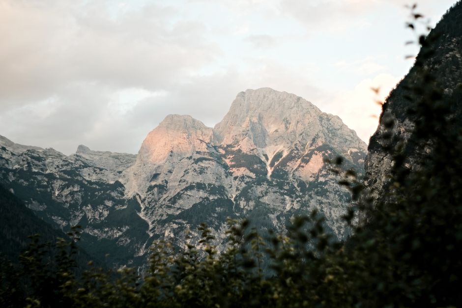 Hikers on a trail in the Julian Alps, Slovenia, with a subtle hint of safety or rescue services in the background