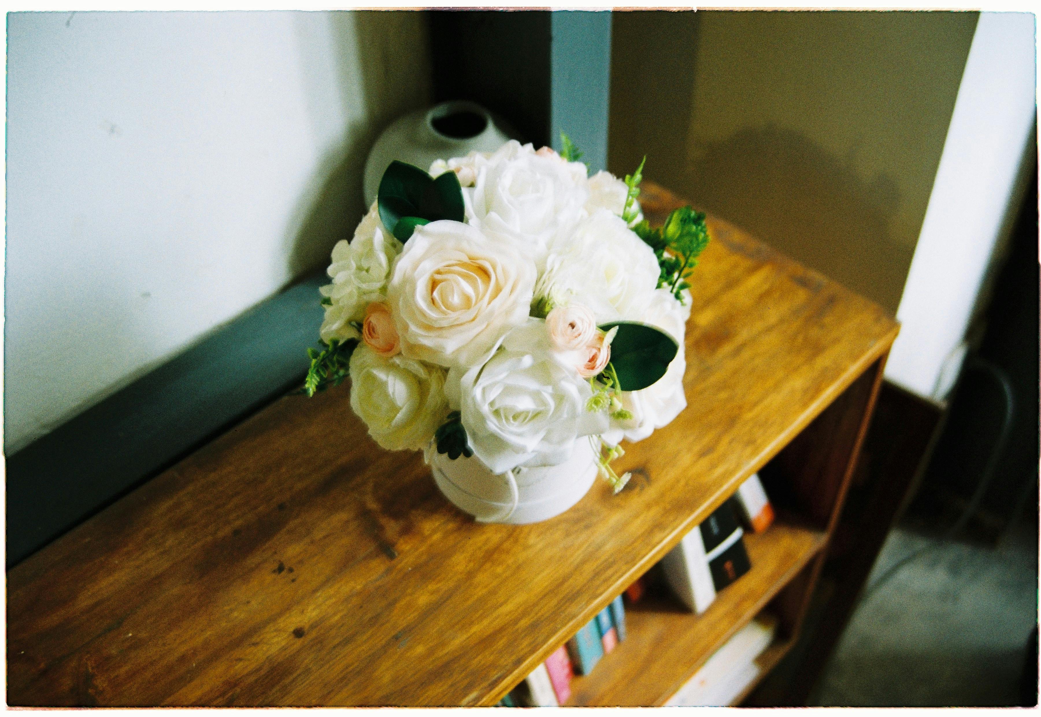 室内木制架子的花瓶里，插着美丽的白色和粉色玫瑰