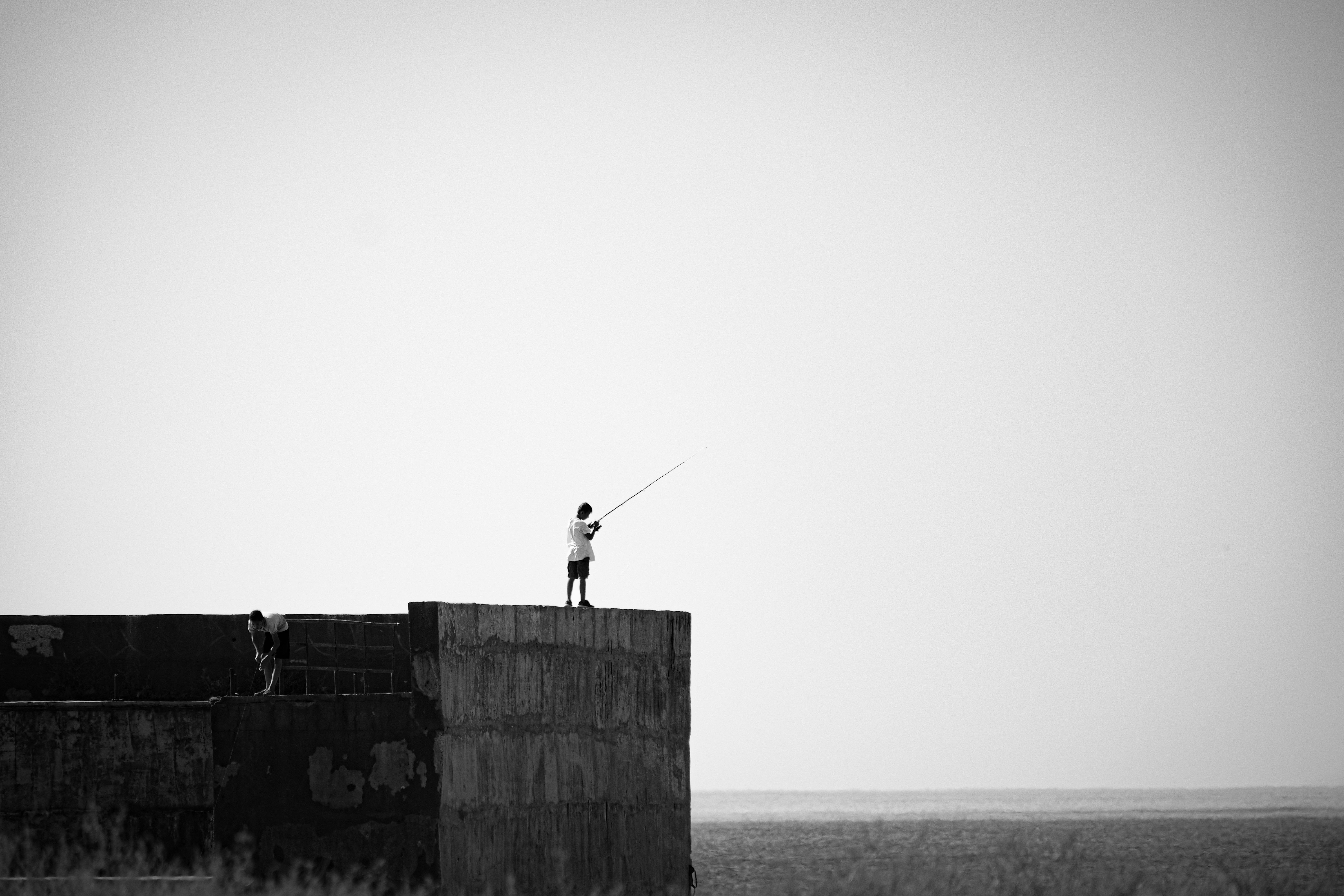 A minimalist black and white photo of fishing at the coast in Aktau, Kazakhstan.