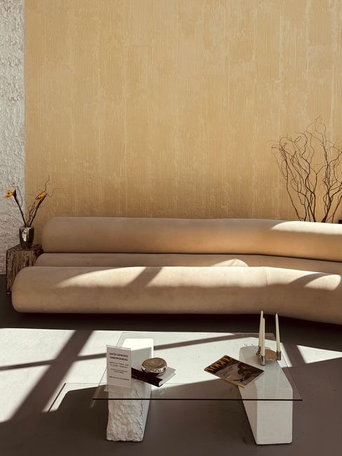 Stylish and modern living room with a beige sofa and artistic decor under natural light.