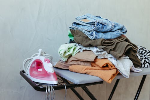 Free Freshly Ironed Clothes on Board with Steam Iron Stock Photo
