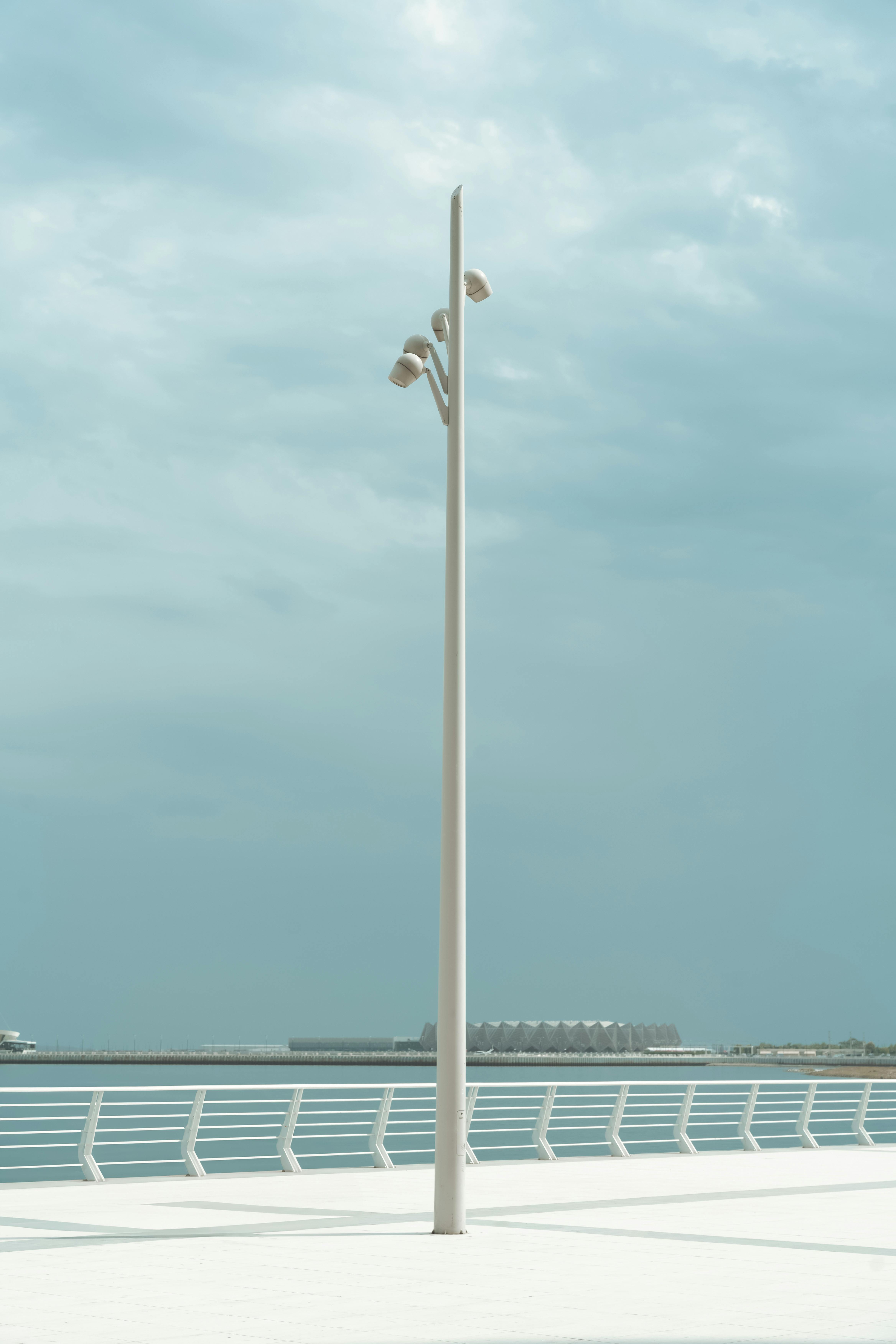 A serene coastal scene with a modern light post and overcast sky.