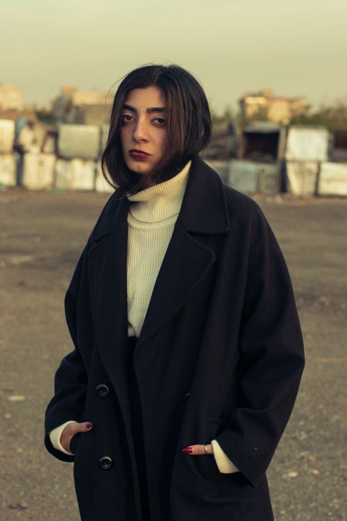 Free Woman in a black coat standing outdoors, moody vibe. Stock Photo