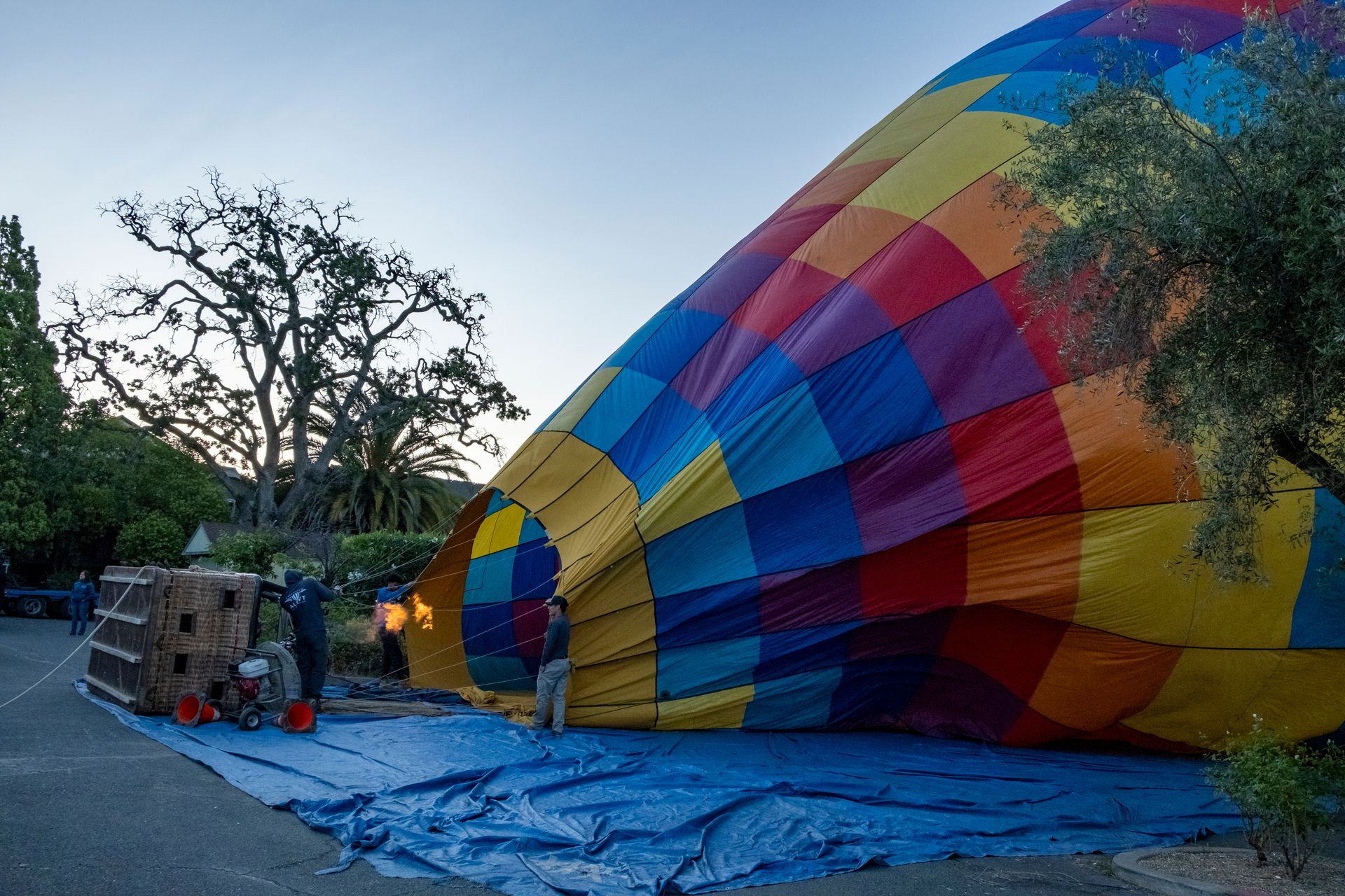 A vibrant hot air balloon is being inflated outdoors in Napa, California at dusk.