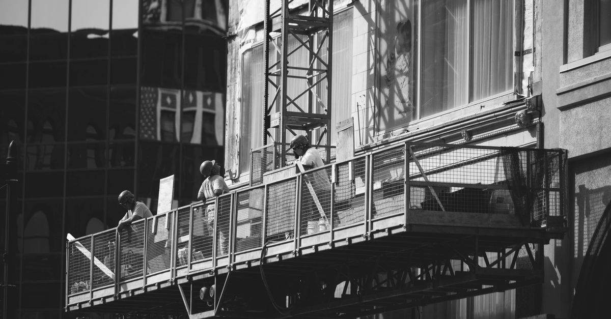 Black and white photo of construction workers on a scaffold in Milwaukee, WI.