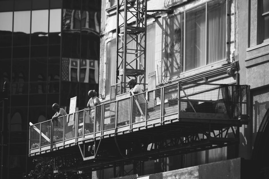 Black and white photo of construction workers on a scaffold in Milwaukee, WI.