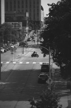 A black and white photo of a motorcyclist riding through a city street in Milwaukee, Wisconsin.