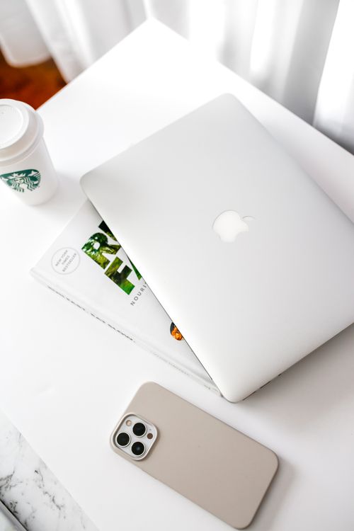 Free Stylish workspace featuring a laptop, smartphone, and coffee cup on a bright desk. Stock Photo