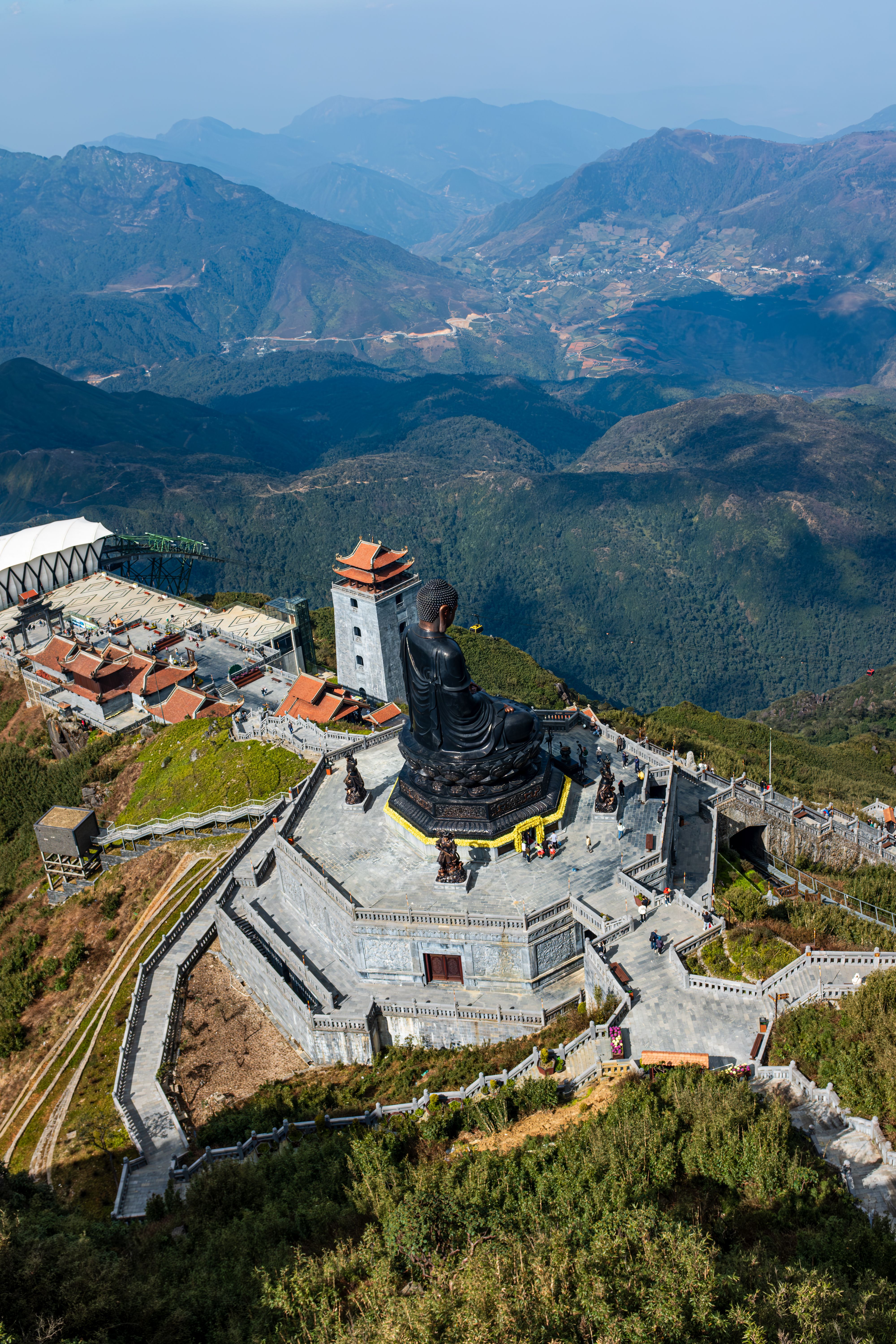 Aerial view of a grand Buddha statue surrounded by Vietnam's scenic mountains.