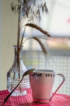 Minimalist coffee cup with vase on a red polka dot cloth for a cozy atmosphere.