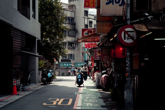 Bustling Taipei street with motorbike, signs in Chinese, and urban vibe.