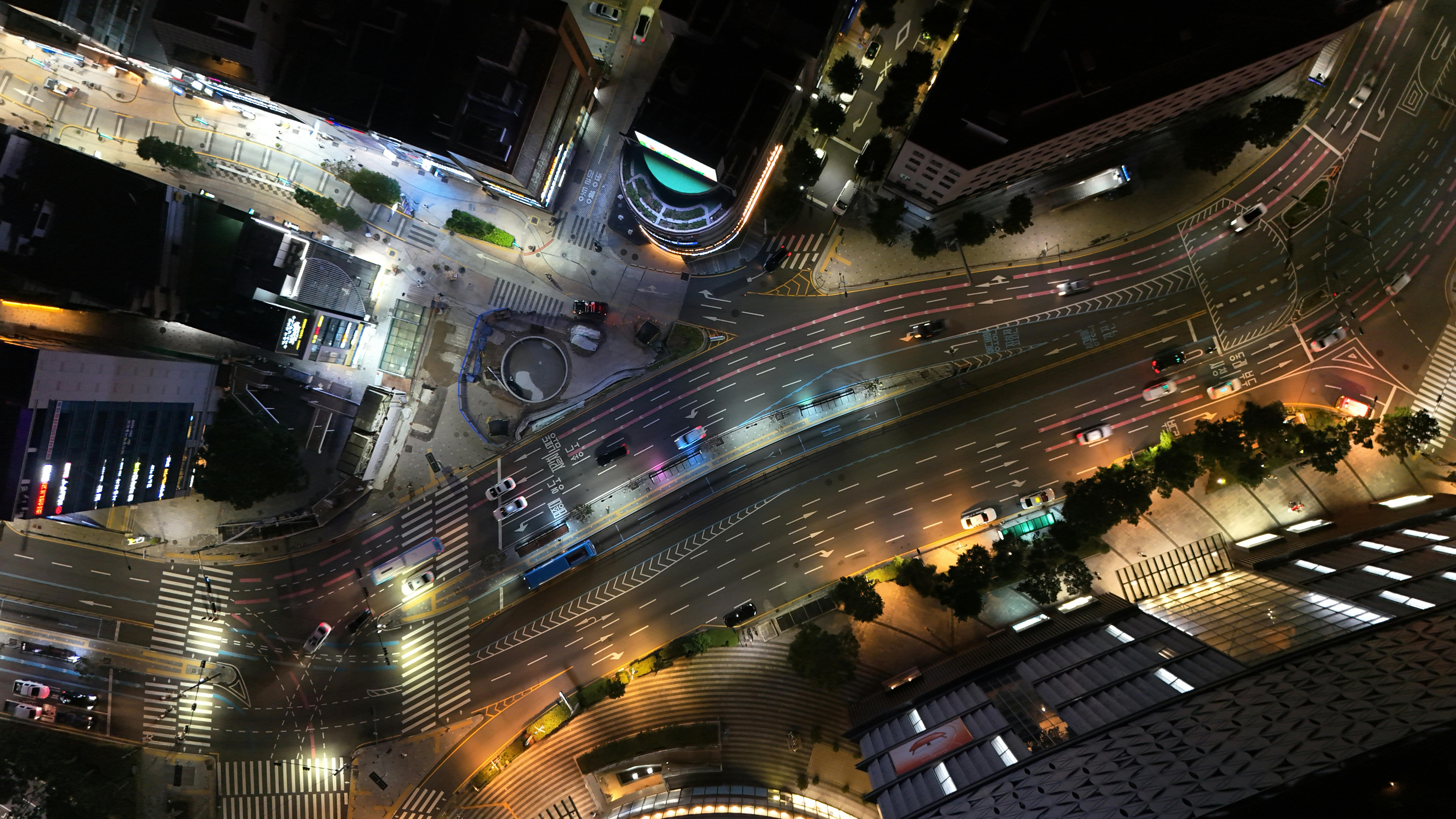A vibrant aerial view of illuminated streets and traffic in Busan at night.