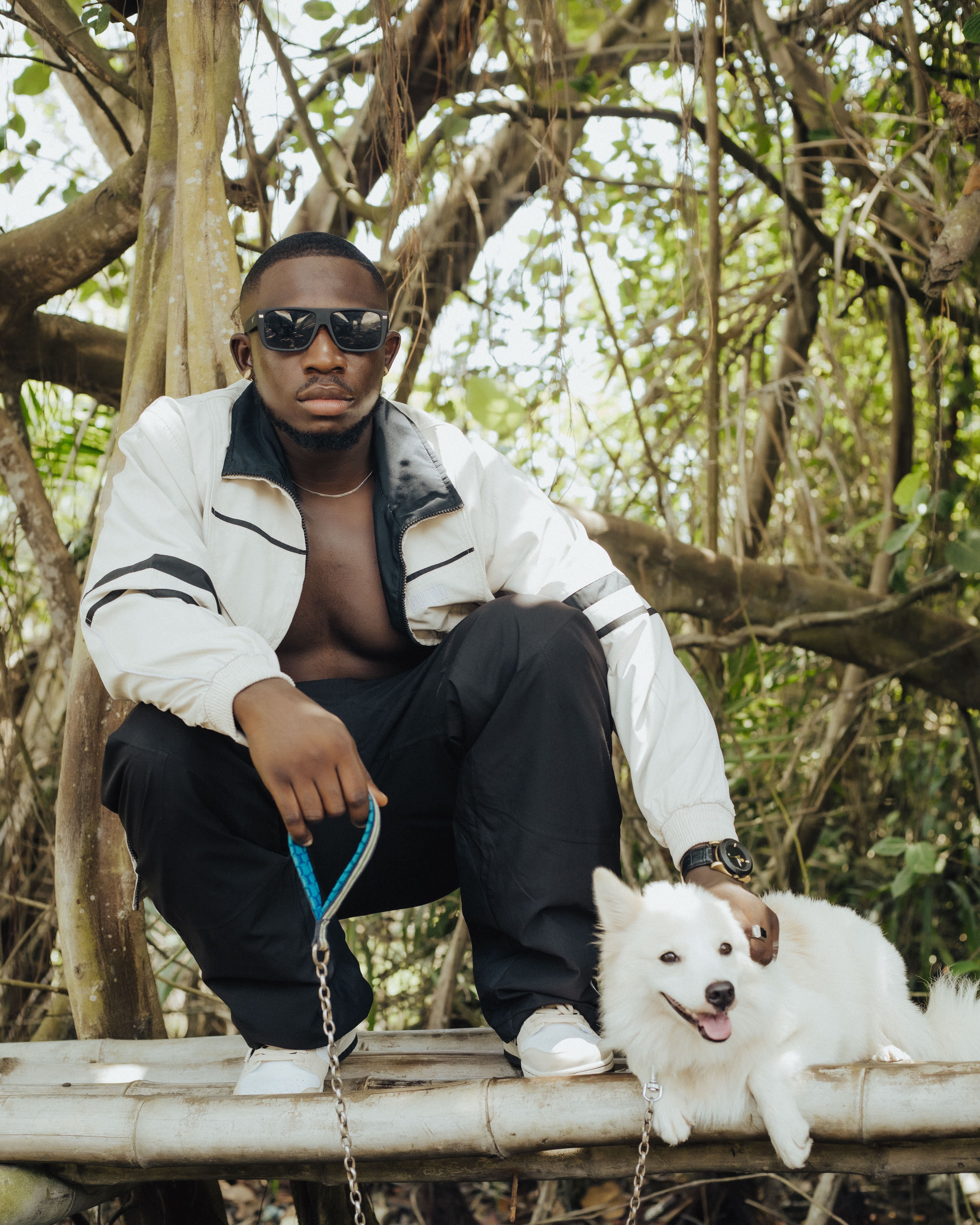 Stylish man with a dog in an outdoor forest setting.