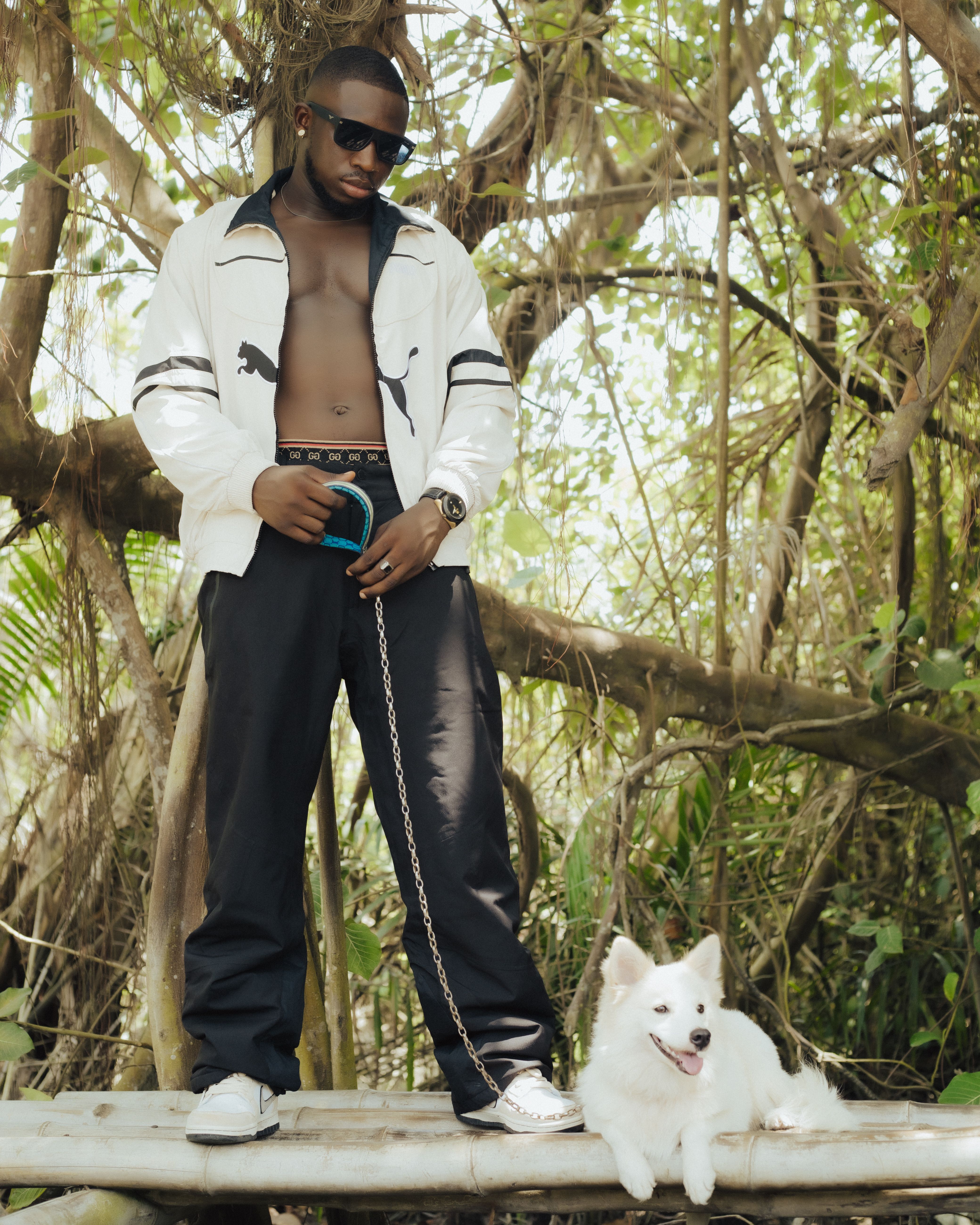 Man in casual outfit with dog in a lush forest area, exuding style and confidence.