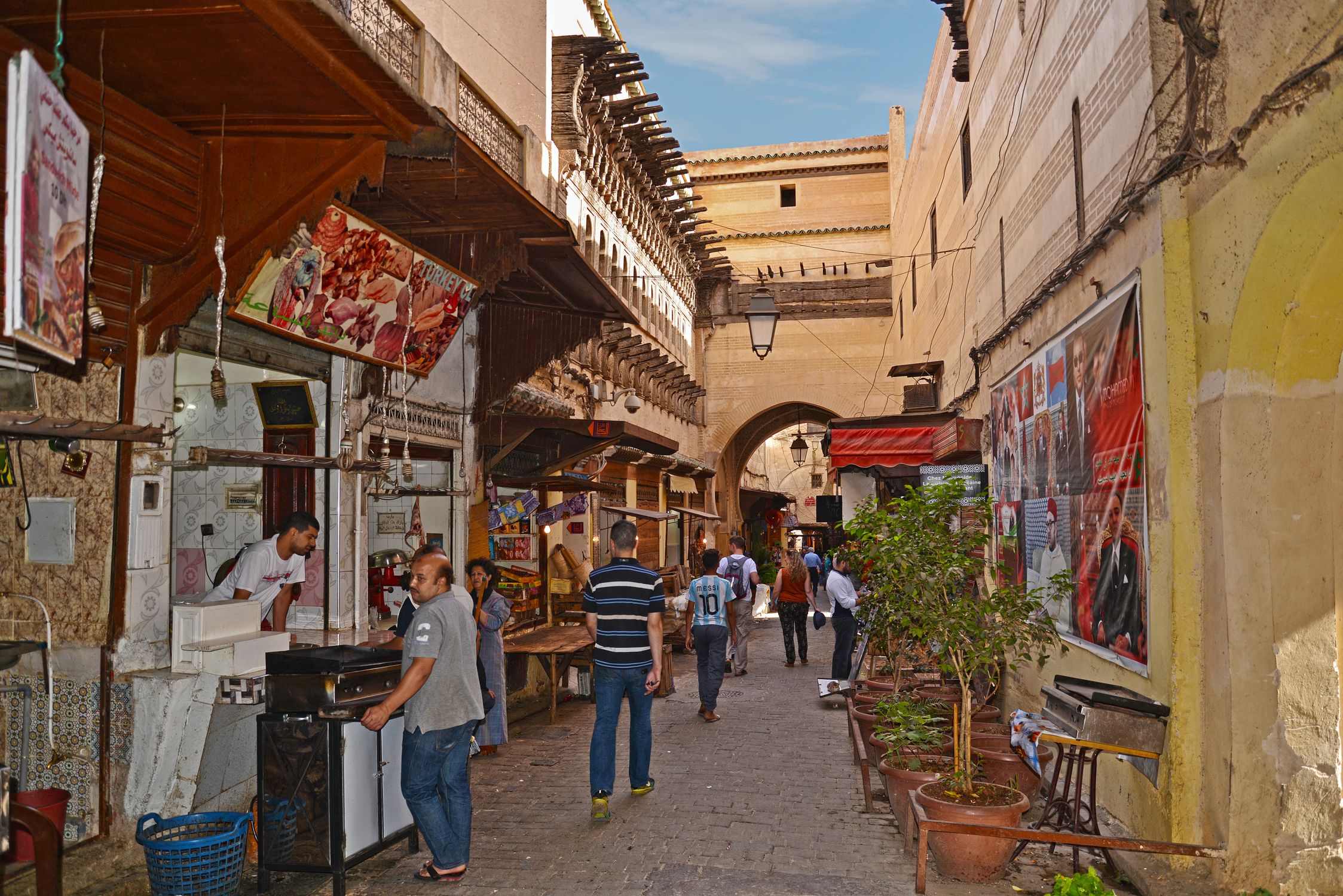 Vibrant street scene in the Medina of Fès, Morocco, with locals and market stalls.
