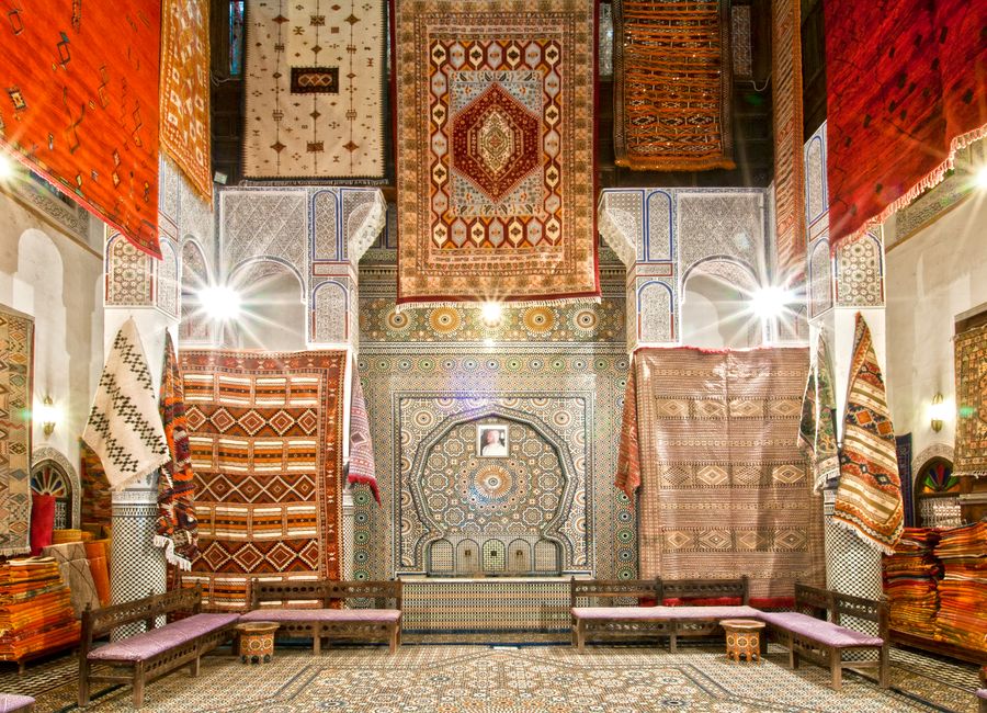 Beautiful display of colorful Moroccan carpets in a traditional shop in Fès, showcasing intricate designs and patterns.