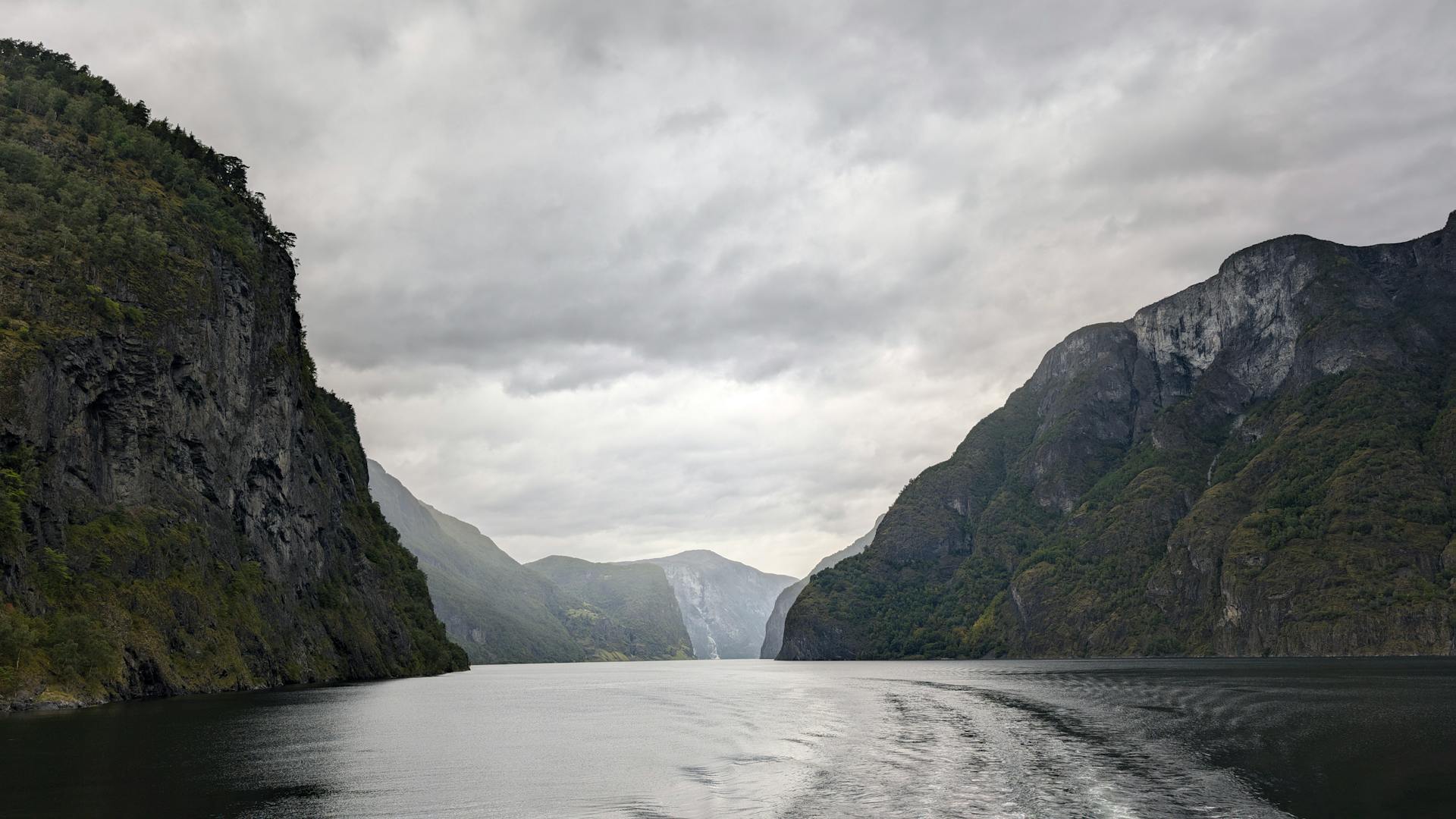 Captivating view of Norway's Bergen fjords with dramatic clouds overhead, showcasing stunning natural beauty.