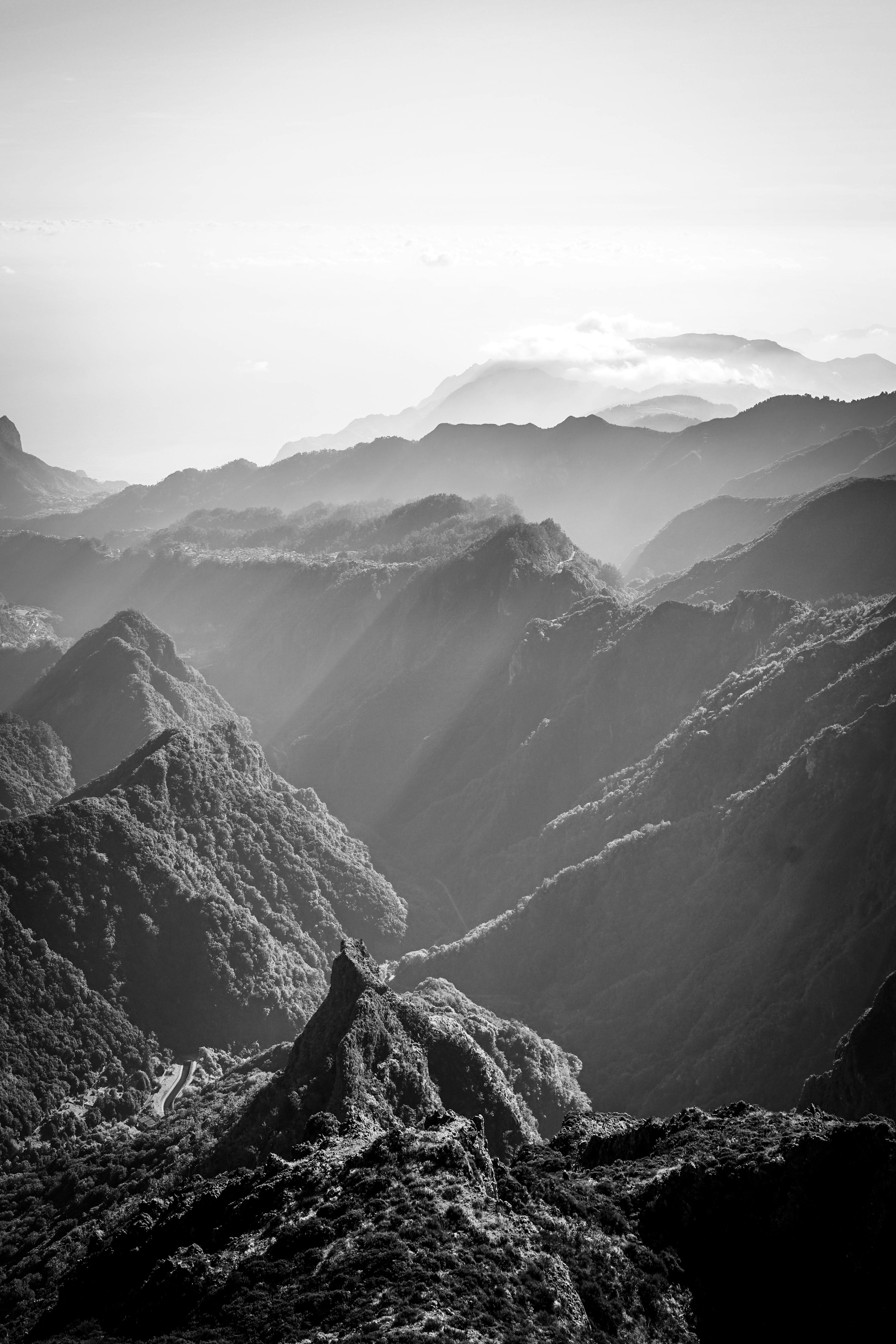 A breathtaking black and white landscape of mountain ranges with mist and dramatic lighting.