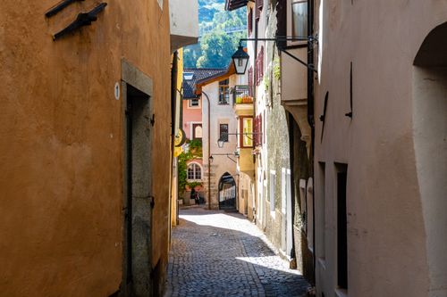 Free Sunlit cobblestone street in an Italian village with rustic buildings and vibrant colors. Stock Photo