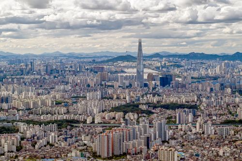 Free Panoramic aerial image of Seoul featuring the iconic Lotte World Tower under cloudy skies. Stock Photo