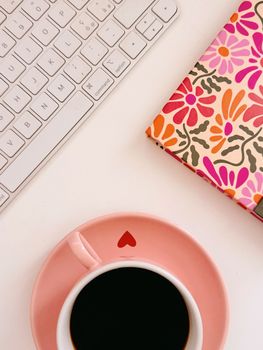 Colorful home office setup featuring coffee, keyboard, and floral planner.