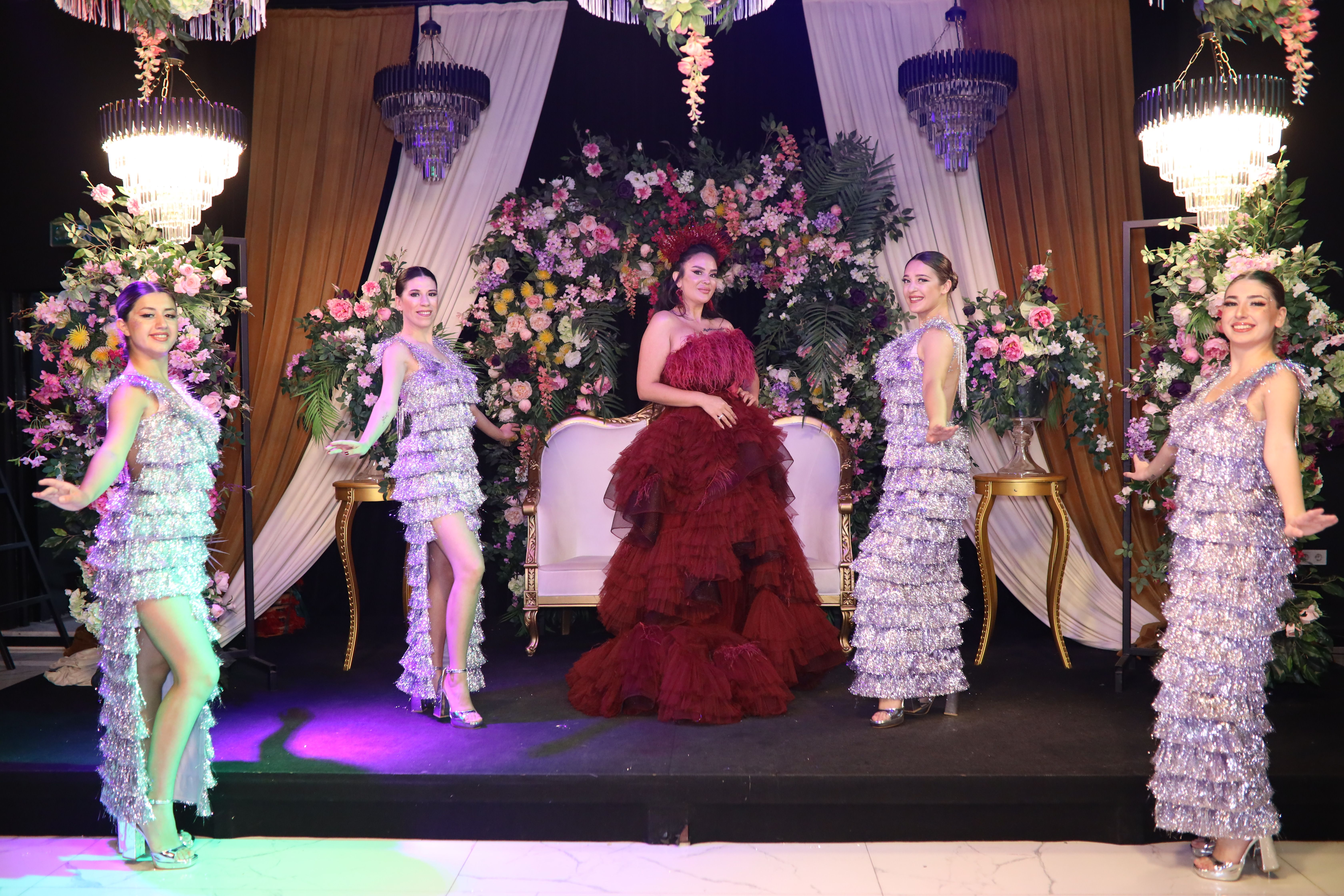 five star hotel event entertainment Cairo — A group of performers in sparkling dresses at a luxurious floral-decorated indoor