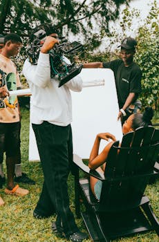 Outdoor film set with crew and camera, capturing a scene with a seated actress.