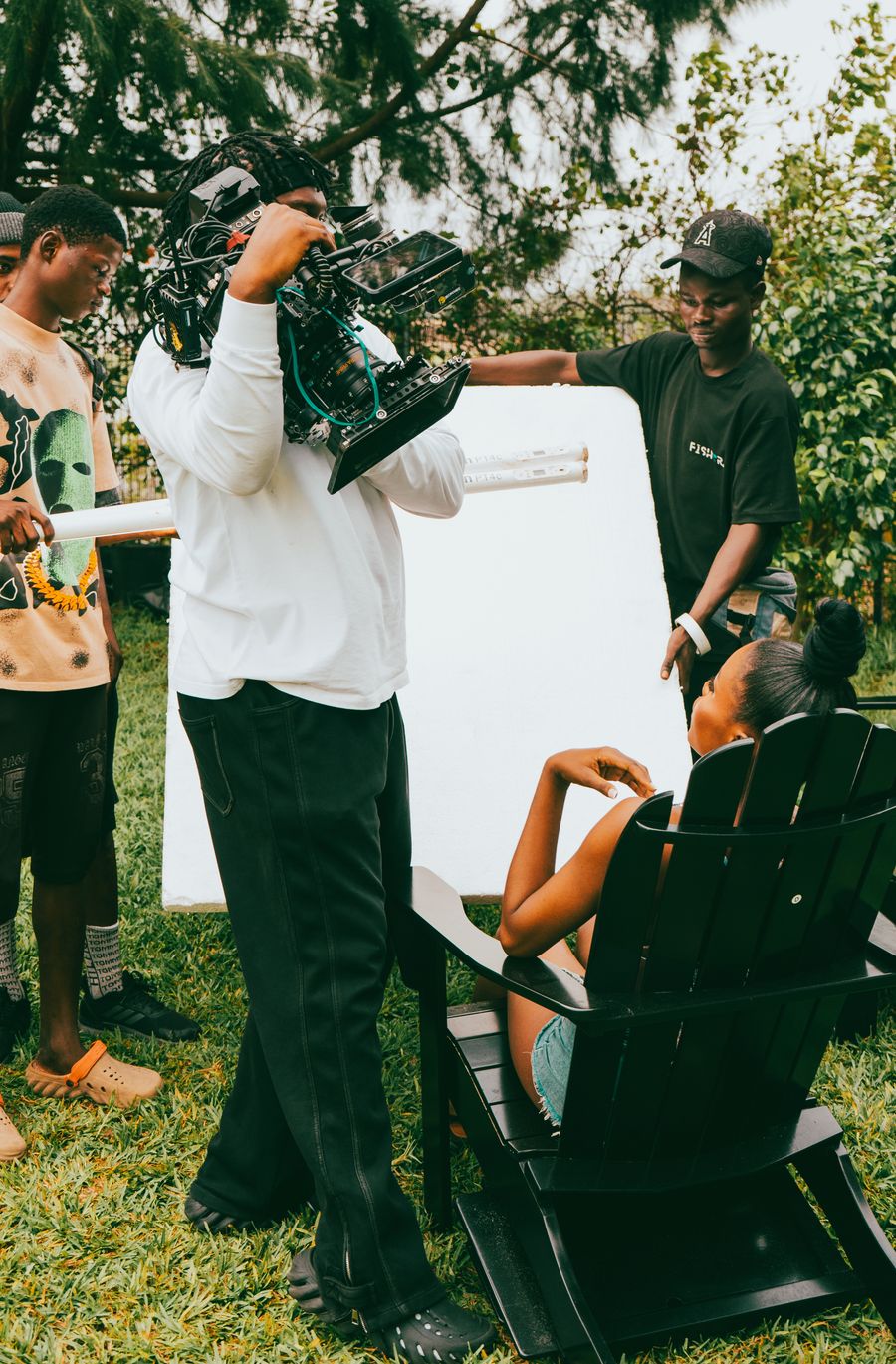 Behind the scenes of an outdoor shoot with a camera operator and bounce board