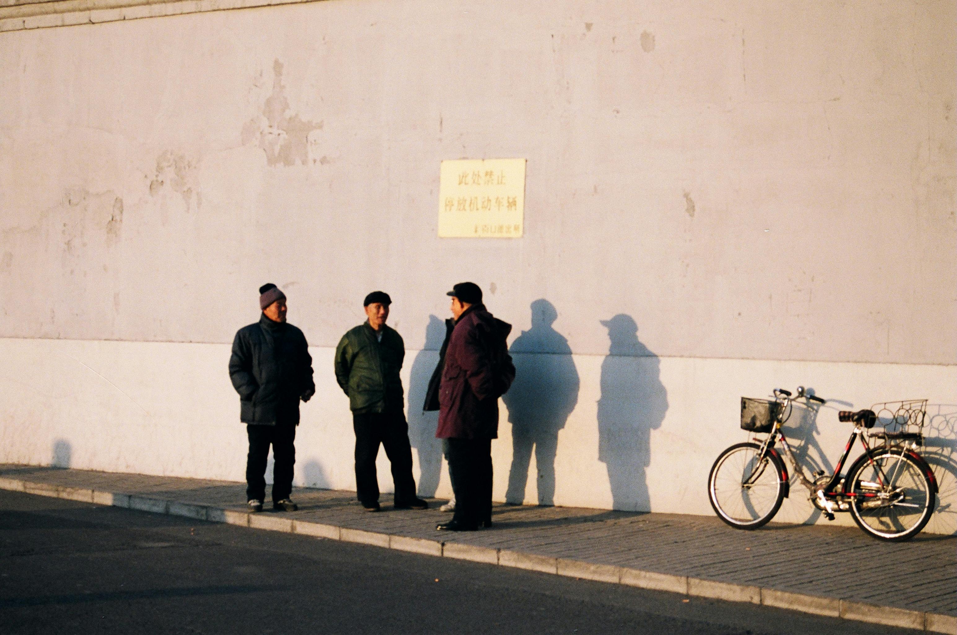 Three men standing near parked bicycle | Photo: Pexels