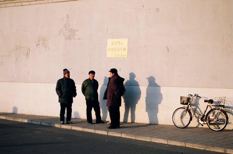 Three Men Standing Near Parked Bicycle