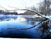 冬日宁静，白雪皑皑的河岸与平静冰冷的河流上倒映着冰霜