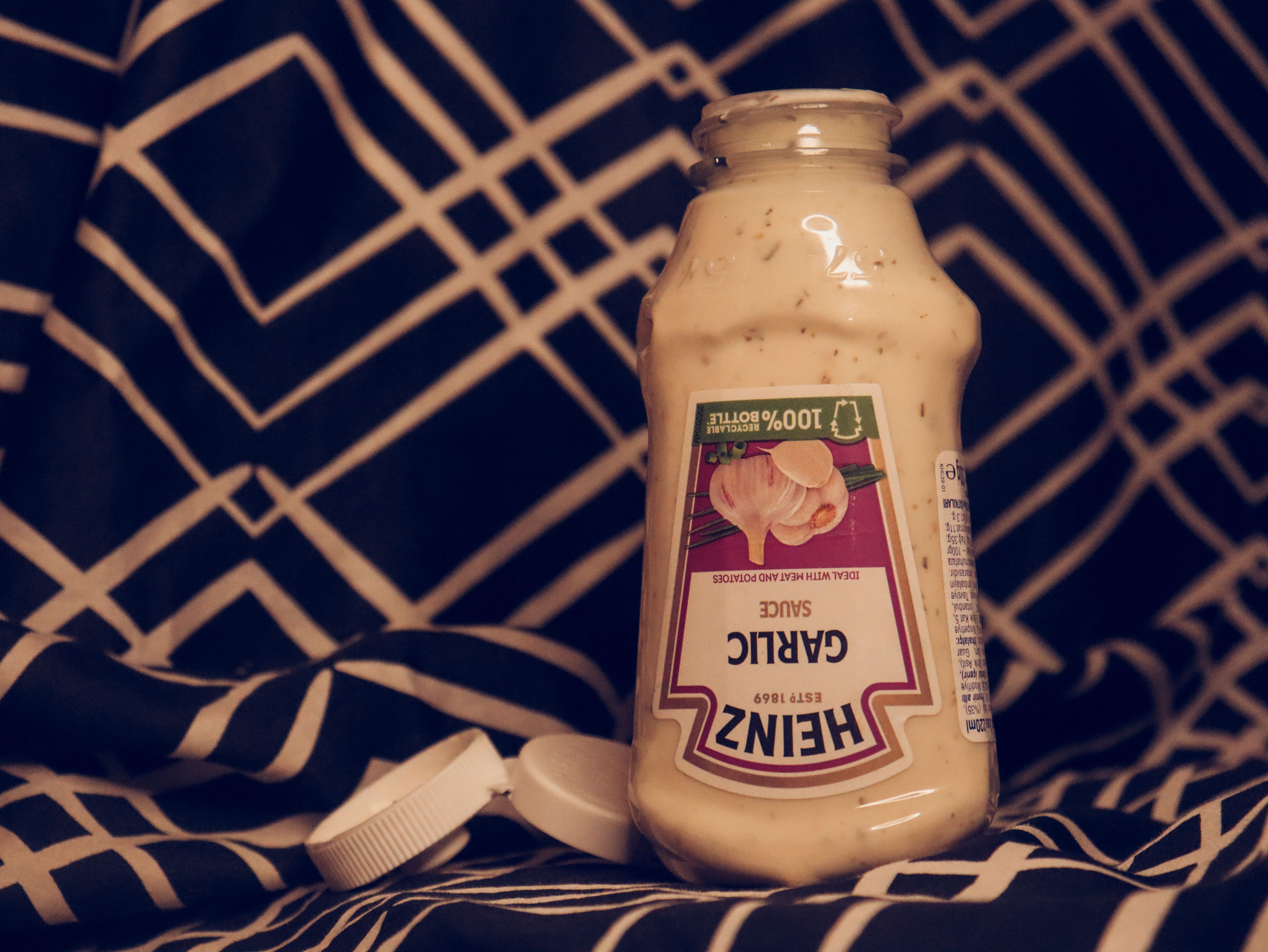Upside-down garlic sauce bottle on a black and white geometric patterned fabric.