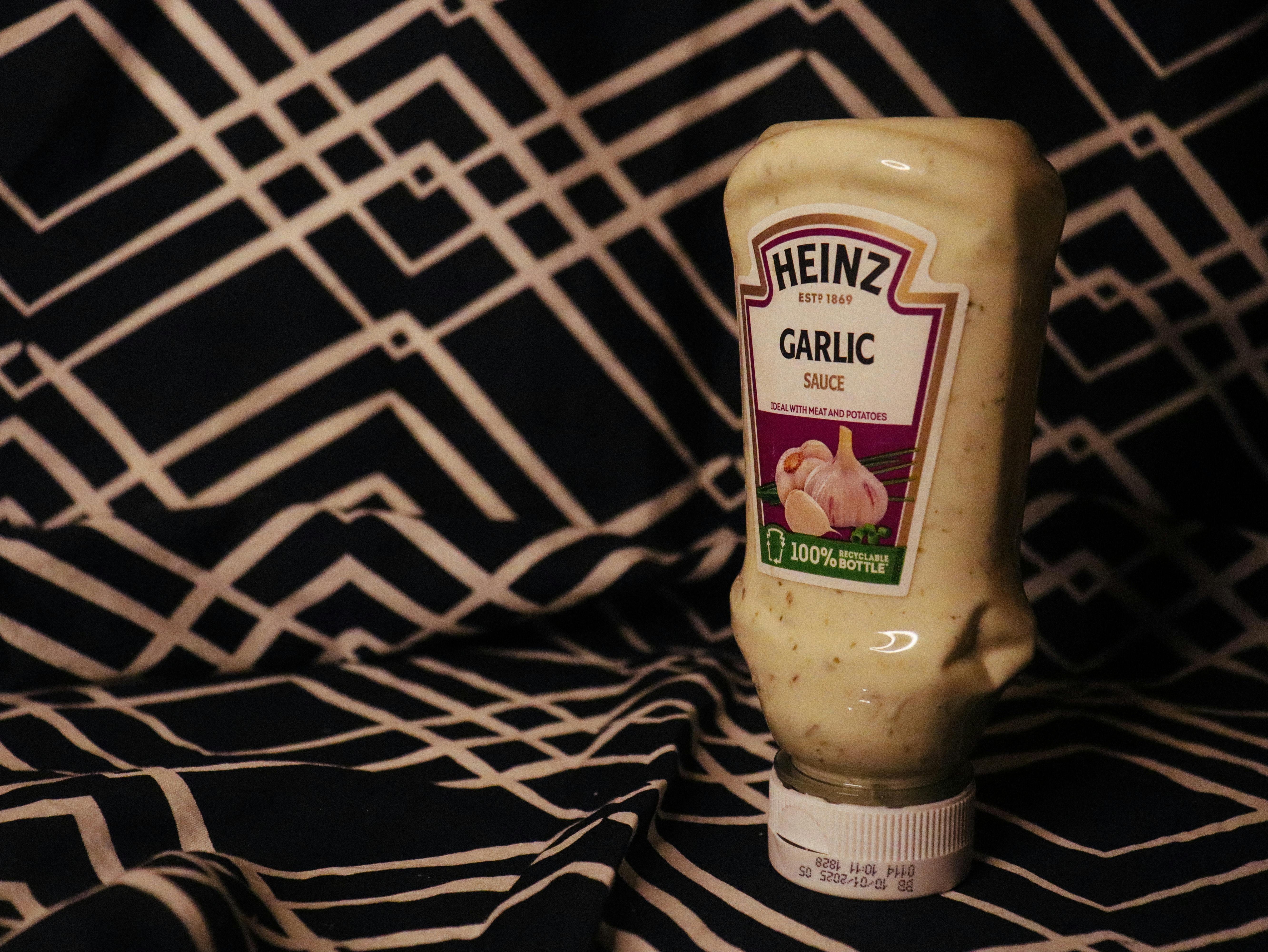 Heinz garlic sauce bottle on black and white geometric patterned fabric.