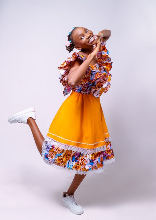 Free Happy woman in a bright floral dress striking a playful pose. Perfect for fashion and lifestyle themes. Stock Photo