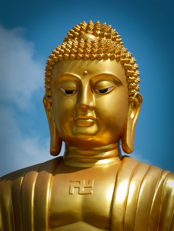 Golden Buddha statue against a blue sky · Free Stock Photo