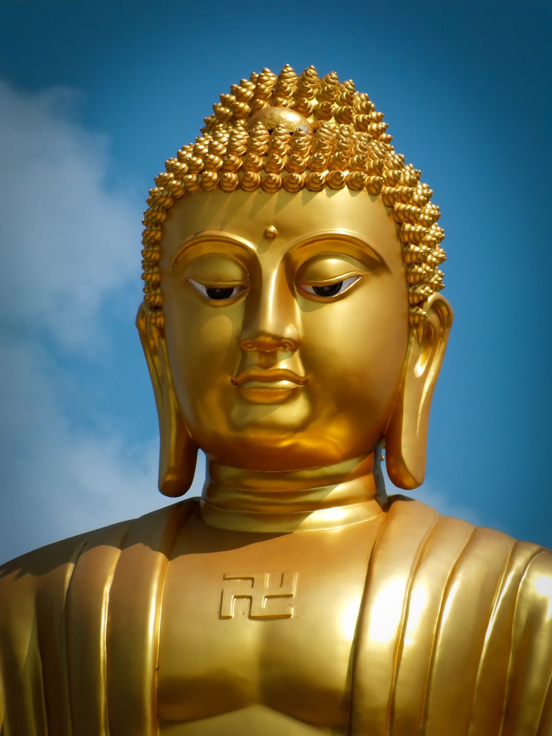 Golden Buddha statue against a blue sky · Free Stock Photo