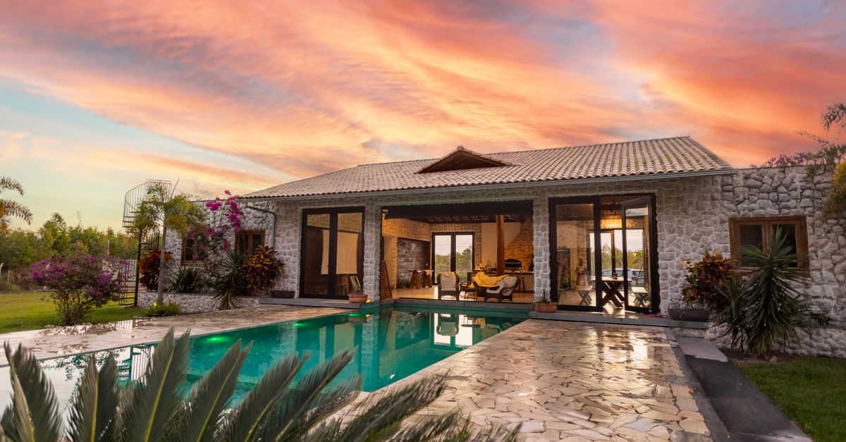 Beautiful stone villa with pool and vibrant sunset sky, perfect for luxury travel.