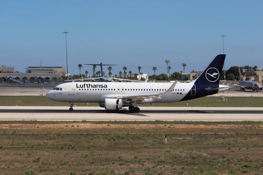Lufthansa Airbus A320 taxiing on a sunny airport runway with palm trees in the background.