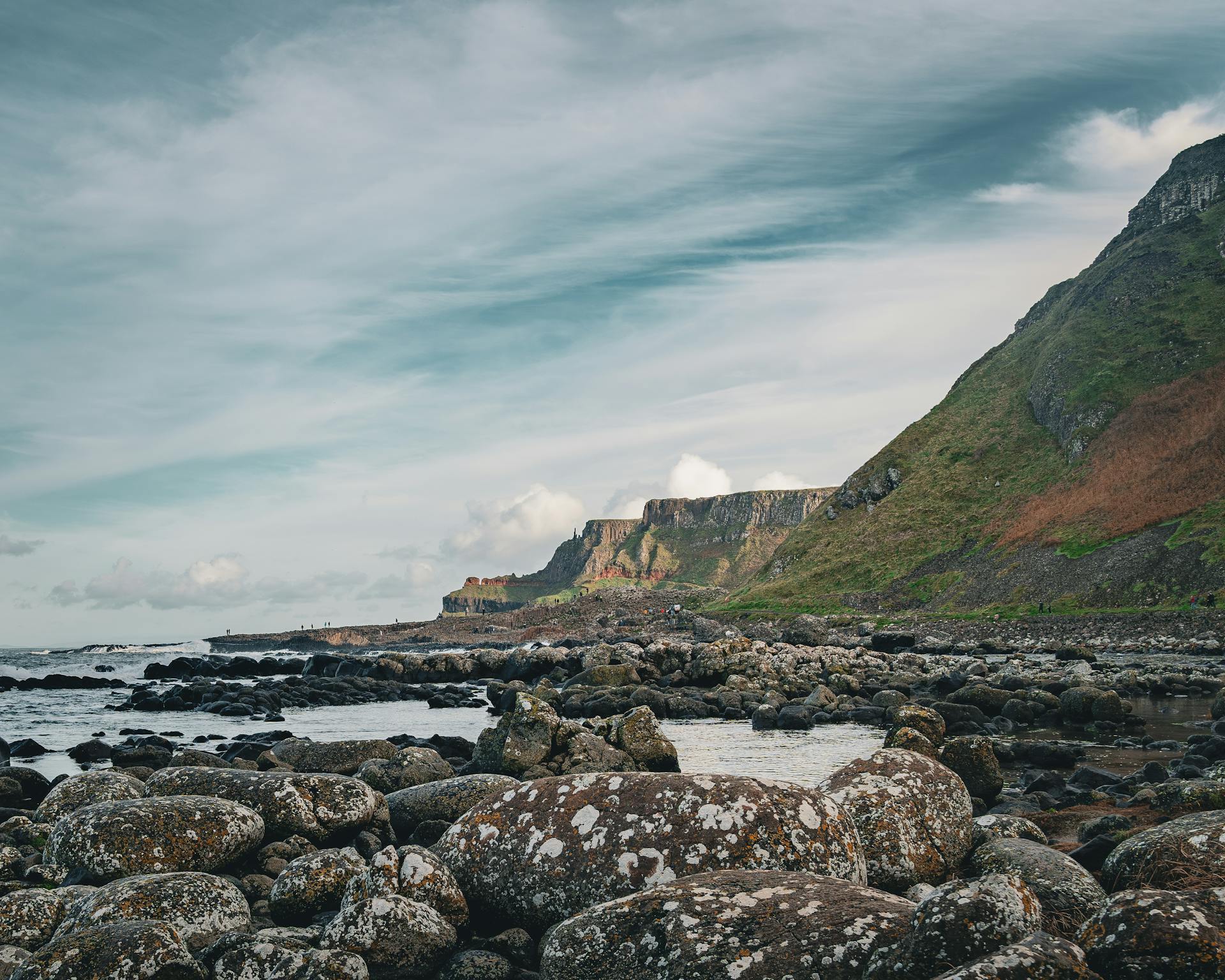 Rugged coastal scene at Giant's Causeway, Northern Ireland with rocky formations and distant cliffs.